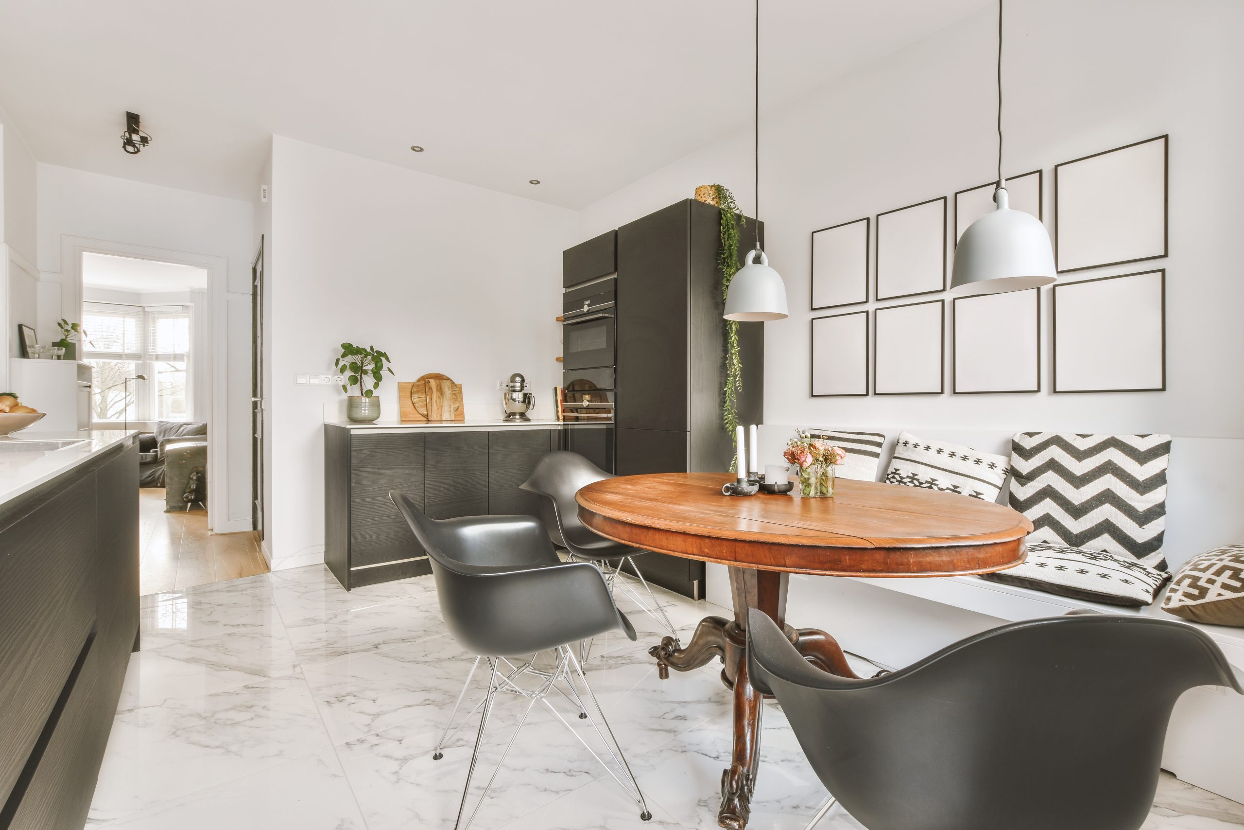 Modern kitchen with black cabinetry and dining area on marble flooring in a luxury apartment.